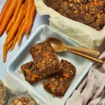 A bowl of healthy carrot cake baked oats topped with nuts and cream cheese frosting.
