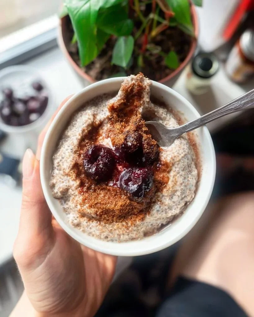 A bowl of Cherry Pie Chia Pudding topped with cherries and almond slices.