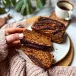Sliced cinnamon swirl pumpkin banana bread on a wooden table