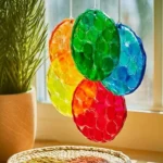 Colorful DIY bioplastic suncatchers hanging in a window