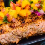 Delicious grilled salmon served with fresh mango salsa on a plate.