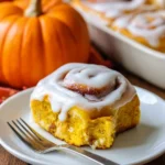 Freshly baked Pumpkin Cinnamon Rolls topped with cream and spices