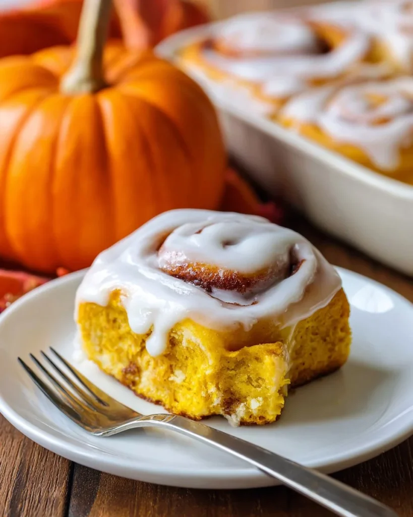 Freshly baked Pumpkin Cinnamon Rolls topped with cream and spices
