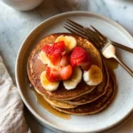 Fluffy Vanilla Protein Pancakes on a plate topped with fresh berries
