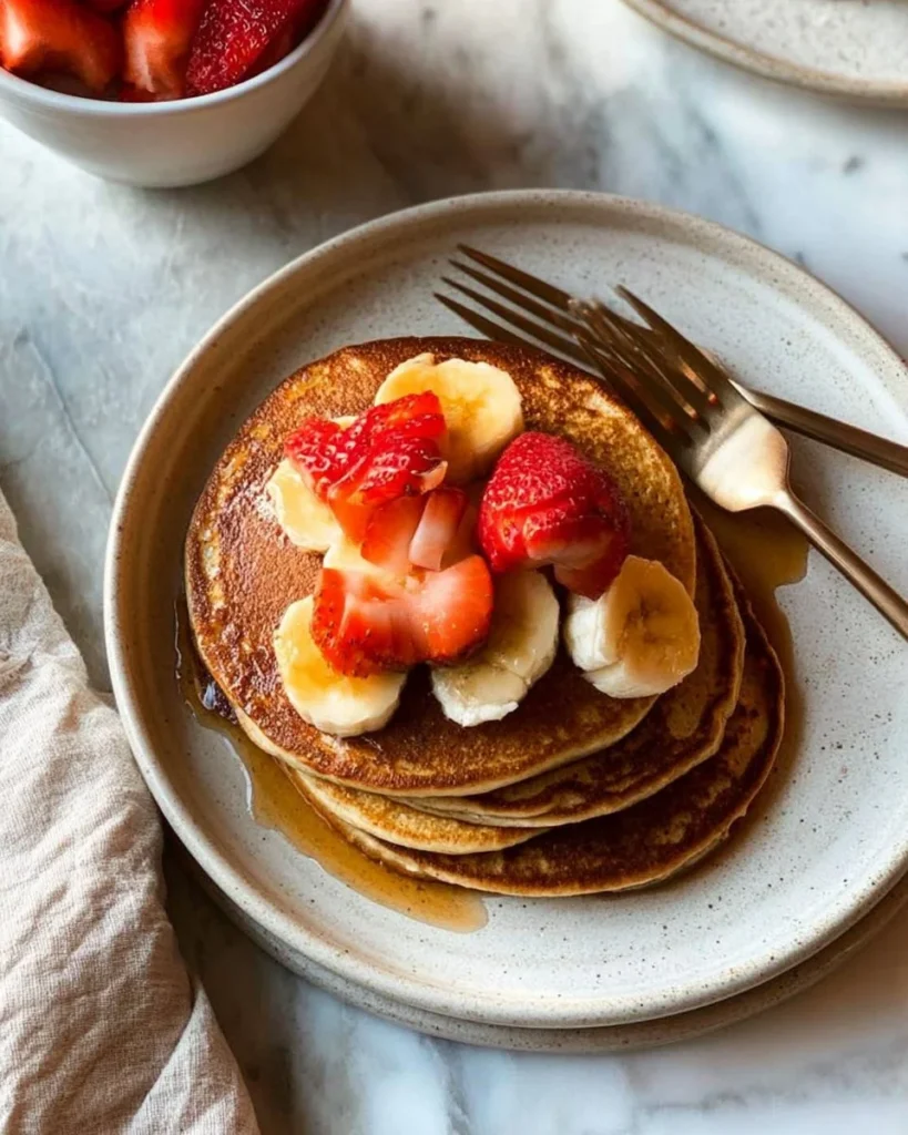 Fluffy Vanilla Protein Pancakes on a plate topped with fresh berries
